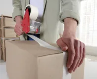 Aplicação de fita adesiva para embalagem em caixa de papelão com aplicador manual.